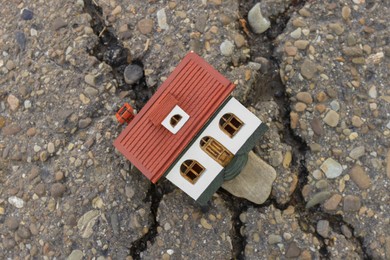 House model in cracked asphalt, top view. Earthquake disaster