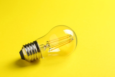 Vintage filament lamp bulb on yellow background