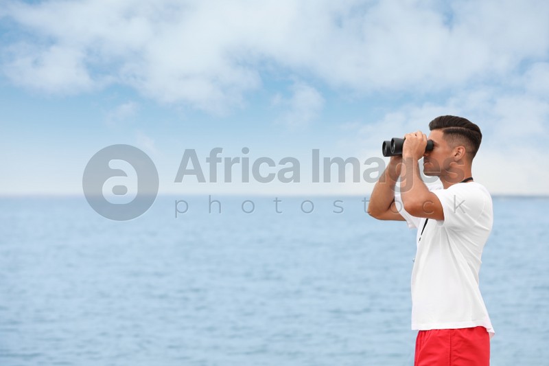 Handsome male lifeguard with binocular near sea