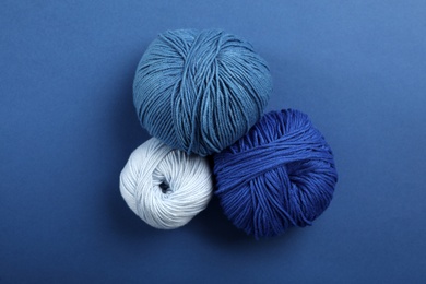 Soft woolen yarns on blue background, flat lay