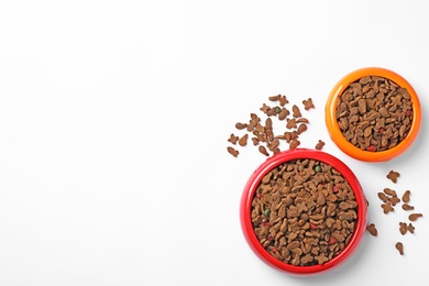 Bowls of dry pet food on white background, top view
