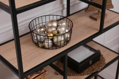 Photo of Stylish shelving unit with Christmas balls indoors. Interior design