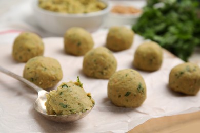 Raw falafel balls and spoon on parchment, closeup
