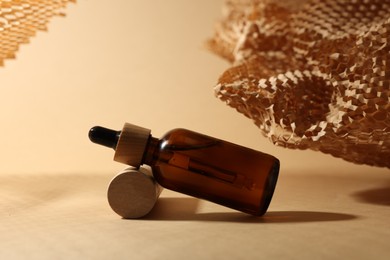 Photo of Glass bottle of essential oil on dark beige background