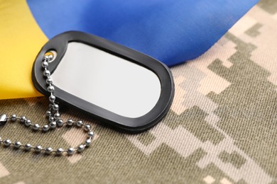 Photo of Military ID tag and Ukrainian flag on pixel camouflage, closeup