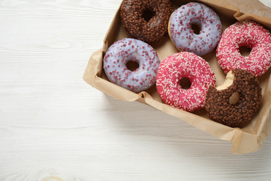 Delicious glazed donuts on white wooden table, top view. Space for text