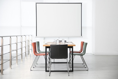 Modern meeting room interior with large table and projection screen