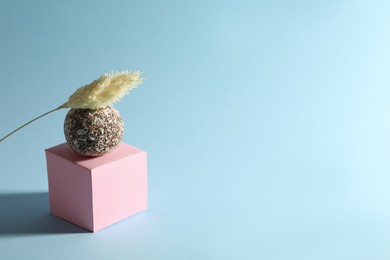 Minimalistic composition with delicious vegan candy ball on light blue background. Space for text