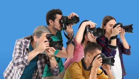 Group of professional photographers with cameras on light blue background