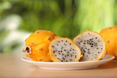 Photo of Delicious cut and whole dragon fruits (pitahaya) on wooden table, closeup