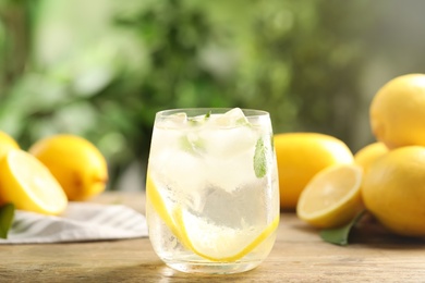 Photo of Cool freshly made lemonade in glass on wooden table
