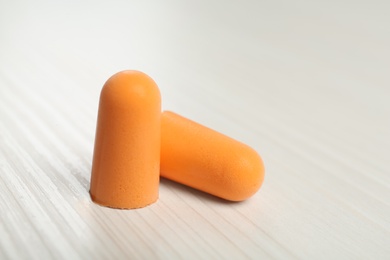 Pair of ear plugs on white wooden background, closeup