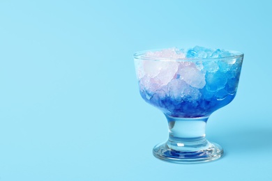 Shaving ice in glass dessert bowl on light blue background, closeup. Space for text