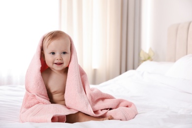 Cute little baby with soft pink towel on bed after bath. Space for text 