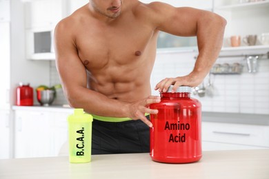 Young athletic man preparing amino acids drink in kitchen