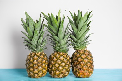 Photo of Fresh ripe juicy pineapples on light blue wooden table