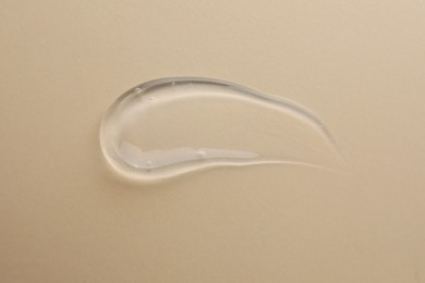 Photo of Sample of transparent gel on beige background, top view