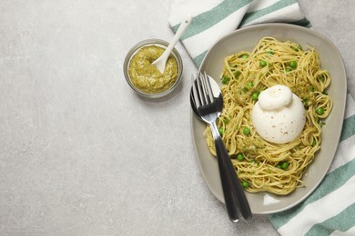 Photo of Delicious spaghetti with burrata cheese, peas and pesto sauce on light grey table, flat lay. Space for text