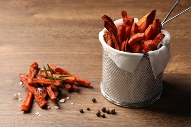 Frying basket with sweet potato fries on wooden table