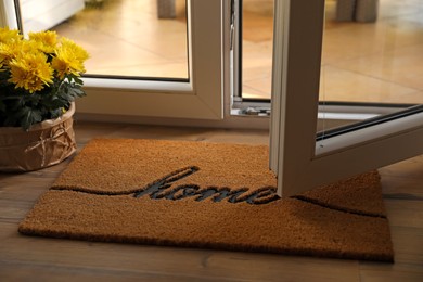 Photo of Doormat with word Home and flowers on parquet floor indoors