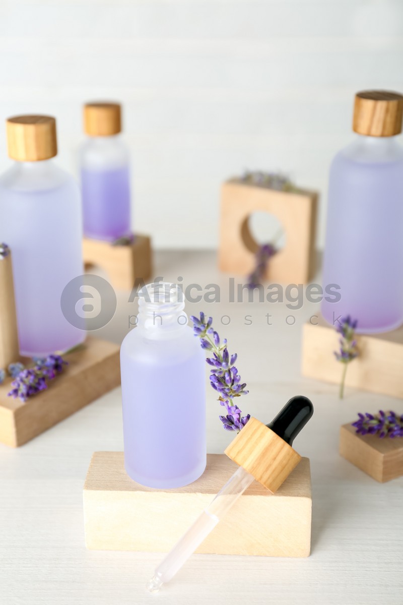 Bottles of lavender essential oil and flowers on wooden table