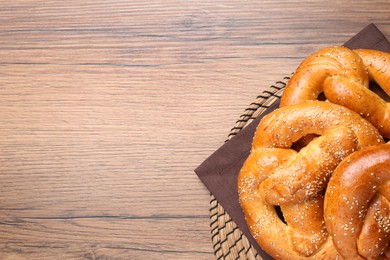 Delicious pretzels with sesame seeds on wooden table, top view. Space for text