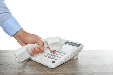 Man dialing number on telephone at table against white background, closeup
