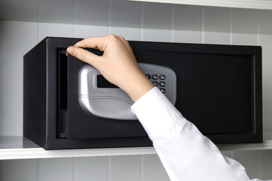 Woman opening black steel safe with electronic lock, closeup