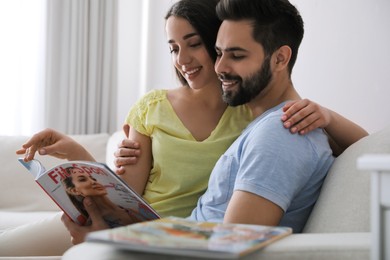 Young couple reading sports magazine on sofa at home