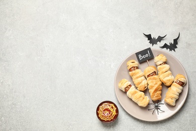 Spooky sausage mummies for Halloween party served on light grey table, flat lay. Space for text
