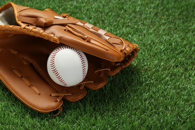Photo of Catcher's mitt and baseball ball on green grass, space for text. Sports game