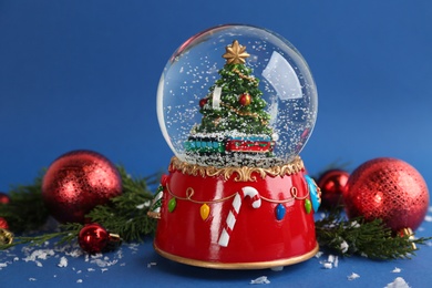 Beautiful snow globe, Christmas balls and coniferous twigs on blue background