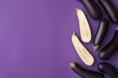 Photo of Raw ripe eggplants on violet background, flat lay. Space for text