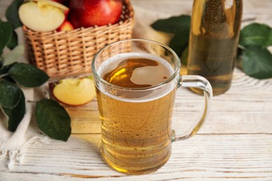 Delicious apple cider in glass mug on white wooden table
