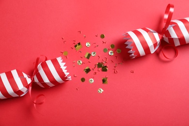Open Christmas cracker with shiny confetti on red background, top view