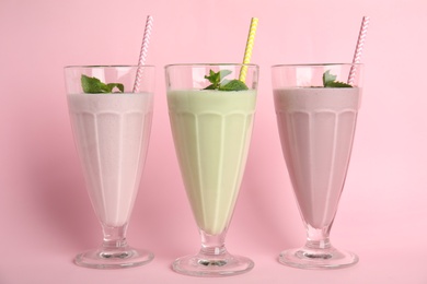 Tasty fresh milk shakes on pink background