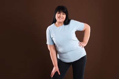 Beautiful overweight mature woman with charming smile on brown background