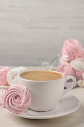 Delicious pink marshmallows and cup of coffee on wooden table