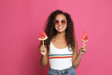 Beautiful young African American woman with pieces of watermelon on crimson background