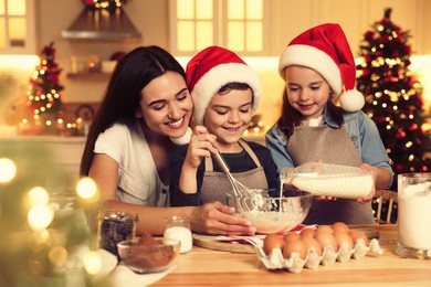 Happy mother and her children making dough for delicious Christmas cookies at home