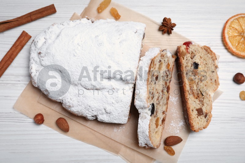 Traditional Christmas Stollen with icing sugar on white wooden table, flat lay