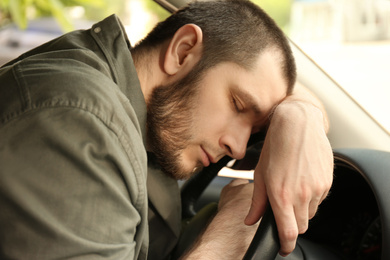 Tired man sleeping on steering wheel in his car