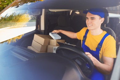 Photo of Courier checking packages in car, view from outside. Delivery service