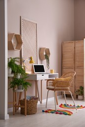 Comfortable workplace with modern laptop and houseplants in room. Interior design
