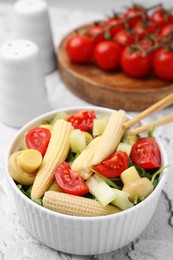 Photo of Tasty baby corn with vegetables and champignons on grey textured table, closeup