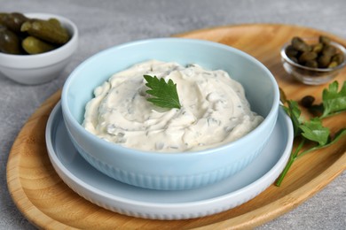 Tasty tartar sauce and ingredients on grey table, closeup