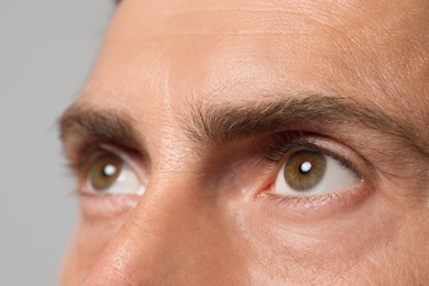 Man with beautiful hazel eyes on grey background, closeup