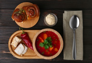 Photo of Delicious borsch served with pampushky and salo on wooden table, flat lay. Traditional Ukrainian cuisine