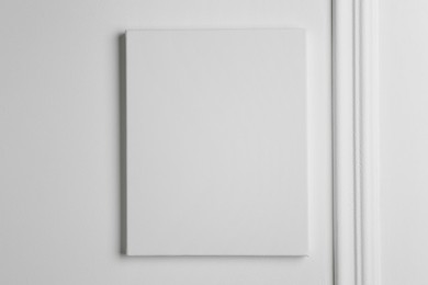 Blank canvas hanging on white wall, space for text
