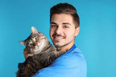 Veterinarian doc with cat on color background